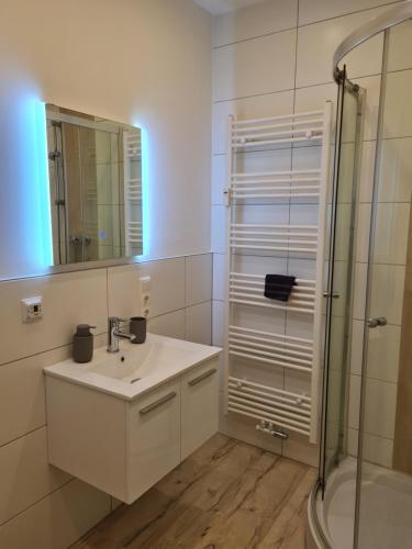 een witte badkamer met een wastafel en een douche bij Ferienwohnung am Kurpark in Bad Rothenfelde