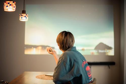 a woman sitting at a table looking at a painting at Manabi-stay Takayama SAKURA in Takayama