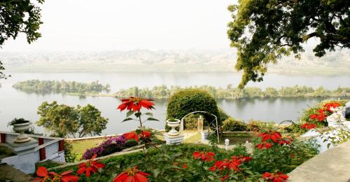 a garden with flowers and a view of a lake at Brijraj Bhawan Palace Hotel in Kota
