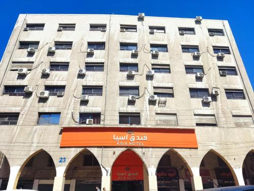un grande edificio con un cartello arancione di fronte di Asia Hotel ad Amman