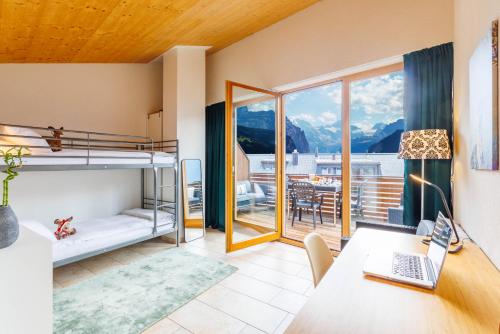 a bedroom with bunk beds and a desk with a laptop at Kinohaus 3 in Wengen