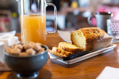 a table with a plate of bread and a glass of orange juice at Le Clos du Piheux in Thorigné-dʼAnjou