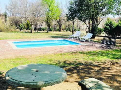 a swimming pool with a table and chairs in a yard at Jackalberry Guest Farm in Parys
