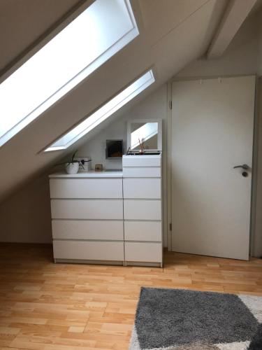 an attic kitchen with a skylight and white cabinets at Zurich Studio in Birmensdorf