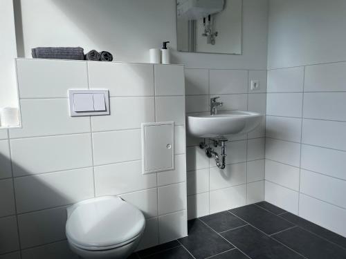 a white bathroom with a toilet and a sink at NorthApartments Chemnitz in Chemnitz