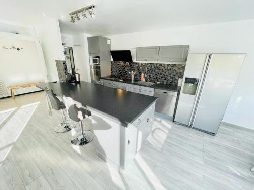 cocina con encimera negra y nevera en Flatshare Colocation 1 close to Geneva, en Saint-Genis-Pouilly