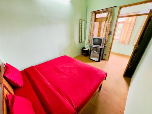 a bedroom with a red bed and a television at Grand view lodge and Restaurant Dharamshala - Partial Prepayment required to confirm booking in Dharamshala
