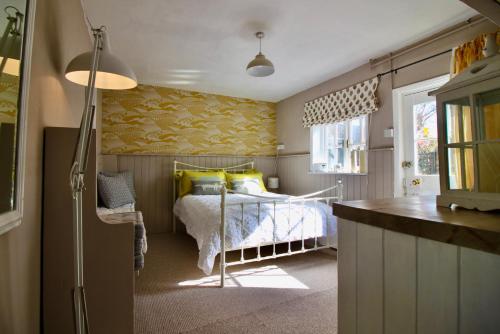 a small bedroom with a bed and a kitchen at The Cottage at Barkwith House in Leiston