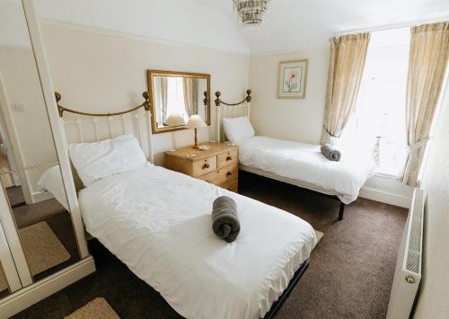 ein Schlafzimmer mit zwei Betten und einem Spiegel in der Unterkunft WILLOW COTTAGE - Cost 3 Bed Cottage in Penrhyn Bay with Sea Views with Access to Snowdonia in Llandrillo-yn-Rhôs