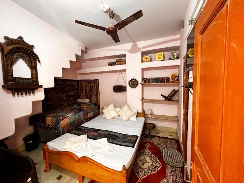 a small room with a bed and a ceiling fan at Marigold Home Stay in Jaisalmer