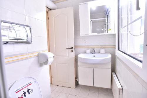 een witte badkamer met een wastafel en een toilet bij Fat Mermaid Seaside Villa in PalaiónTsiflíkion