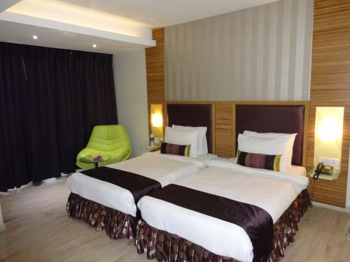 a hotel room with two beds and a green chair at The Purple Leaf Hotels in Hyderabad
