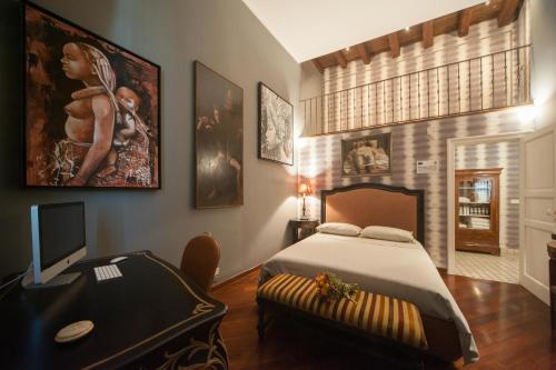 een slaapkamer met een bed en een bureau met een televisie bij Corte Kyrios Exclusive Suite XVIII Secolo in Trani