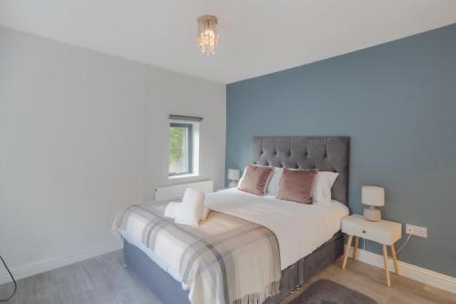 een slaapkamer met een groot bed met een blauwe muur bij Windsor Castle & Shops On Your Doorstep & Parking in Windsor