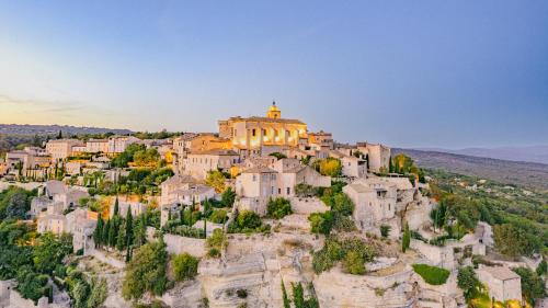 a village on a hill with a church on top at Le Mas Justin in Gordes