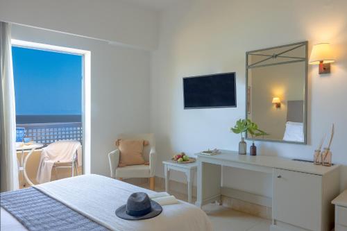 a white bedroom with a desk and a mirror at Giannoulis – Santa Marina Beach Hotel in Agia Marina Nea Kydonias