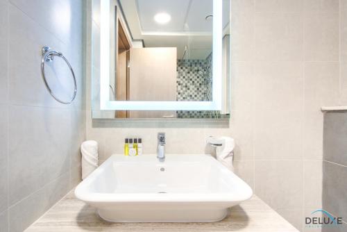 a white sink in a bathroom with a mirror at Homely Studio in Azizi Aliyah Residence Al Jadaf by Deluxe Holiday Homes in Dubai