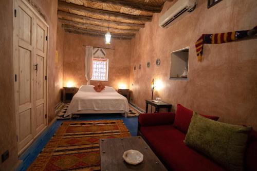 a bedroom with a bed and a couch and a table at Dar Kamar in Ouarzazate