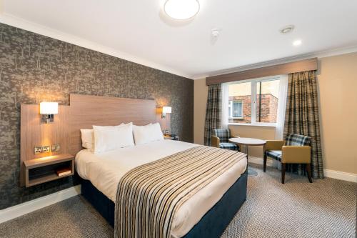 um quarto de hotel com uma cama e uma mesa em Corr's Corner Hotel em Newtownabbey