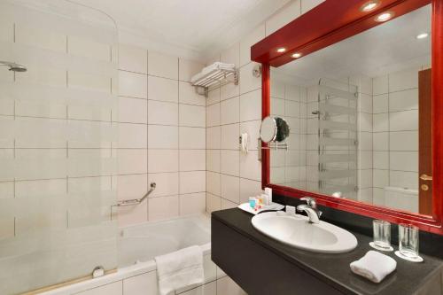 a bathroom with a sink and a mirror and a tub at Ramada by Wyndham Hotel Riyadh in Riyadh