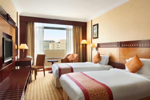 um quarto de hotel com duas camas e uma televisão em Ramada by Wyndham Hotel Riyadh em Riyadh