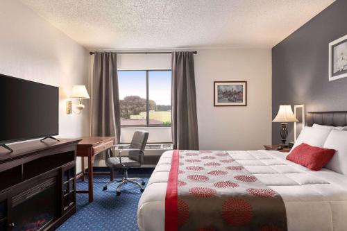 a hotel room with a bed and a desk and a television at Ramada by Wyndham Arcata in Arcata