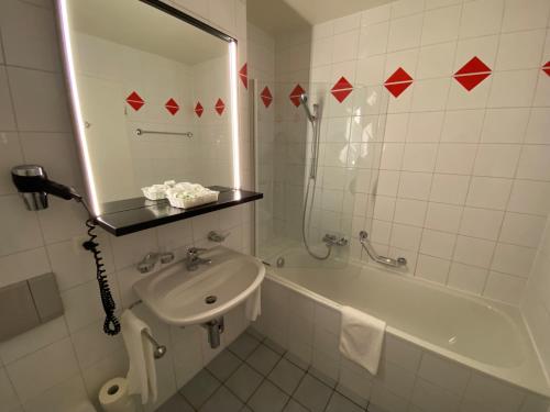een badkamer met een wastafel, een bad en een spiegel bij Studios Astra Hotel Vevey in Vevey