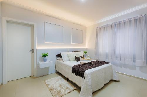 een witte slaapkamer met een bed en een raam bij APT NOVO, LOCALIZAÇÃO PRIVILEGIADA 60 MT DO TERMAS in Piratuba