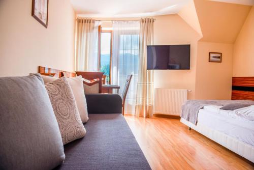 a bedroom with a bed and a couch and a tv at Willa Alesandro in Zakopane