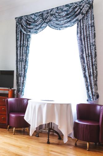 a table and two chairs in front of a large window at Sventes Muiža in Svente