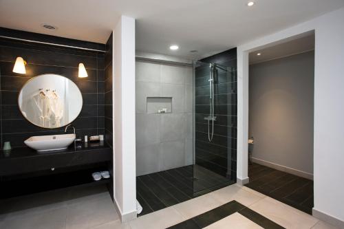 a bathroom with a shower and a sink and a mirror at Le Centell Hotel & Spa in Antananarivo