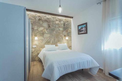 een slaapkamer met een bed met een stenen muur bij Alojamiento Suit Royal in Úbeda