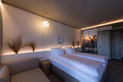 a bedroom with a large white bed and a couch at Hafenhotel zu Putbus in Putbus
