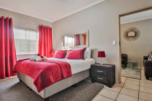 1 dormitorio con 1 cama grande y cortinas rojas en Rudman Townhouses - OR Tambo Airport en Boksburg
