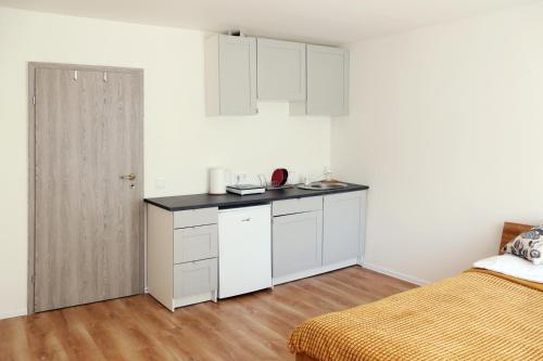 uma cozinha com armários brancos e uma cama num quarto em Naujai suremontuotas butas miesto centre. em Visaginas