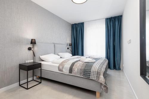 a bedroom with a bed with blue curtains at Sun Towers Lux Apartments by Renters Prestige in Świnoujście