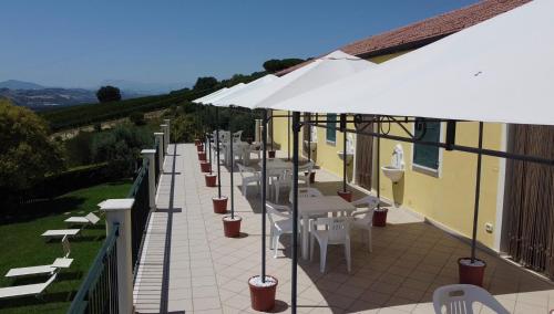 a patio with tables and chairs and an umbrella at Agriturismo MonteMaggio in Lapedona