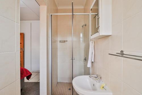 een witte badkamer met een douche en een wastafel bij Rudman Townhouses - OR Tambo Airport in Boksburg