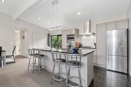 a kitchen with a bar with stools and a refrigerator at Tutukaka Treat - Wellingtons Bay Holiday Home in Tutukaka