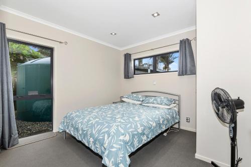 a bedroom with a bed and a fan and a window at Tutukaka Treat - Wellingtons Bay Holiday Home in Tutukaka
