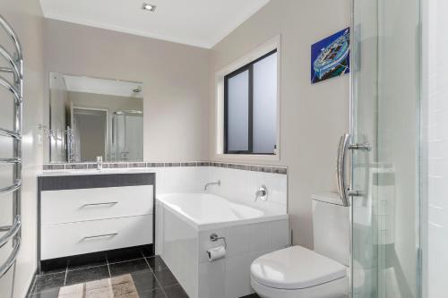 Baño blanco con lavabo y aseo en Tutukaka Treat - Wellingtons Bay Holiday Home, en Tutukaka