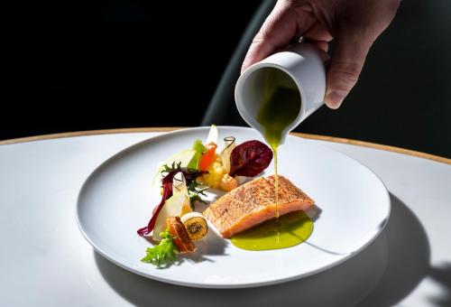 a person pouring a cup of tea onto a plate of food at Hotel Kö59 Düsseldorf - Member of Hommage Luxury Hotels Collection in Düsseldorf