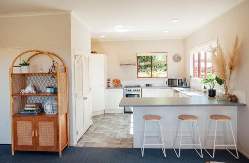a kitchen with a counter and stools in it at Kakariki by the sea in Ngunguru