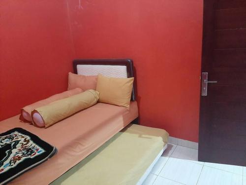 a small couch with pillows on a red wall at Dee homes singaraja in Singaraja