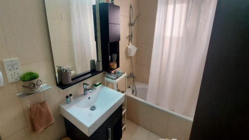 a bathroom with a sink and a tub and a mirror at Paramount Gardens Resorts C202 in Larnaka
