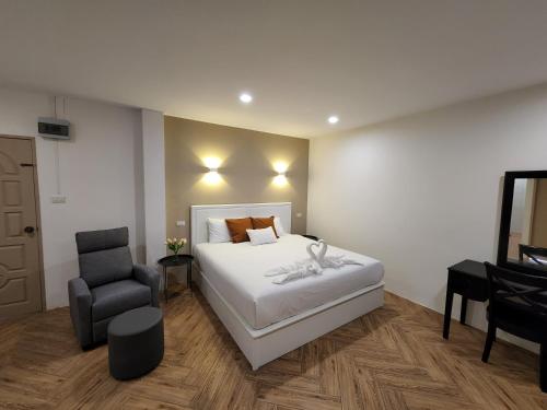 a bedroom with a white bed and a chair at Hommory Residence - West Chalong in Ban Klang