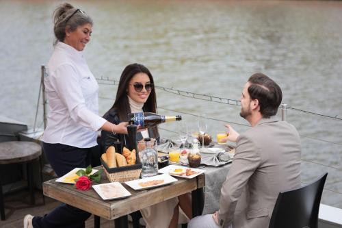 Eine Frau, die Wein an einem Tisch auf einem Boot gießt. in der Unterkunft Hotel Restaurant Brasserie Feestzaal Ahoi, Kortrijk in Kortrijk