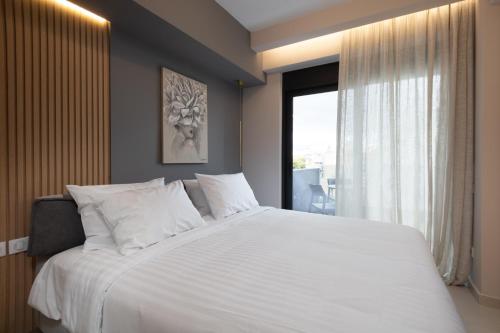 sypialnia z dużym białym łóżkiem i oknem w obiekcie LUX&EASY Athens Downtown Residences w Atenach
