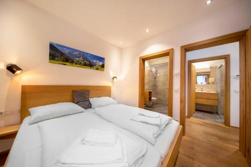 a large white bed in a room with a bathroom at FamilienWohnung Wildspitze am Sonnenhang in Neukirchen am Großvenediger