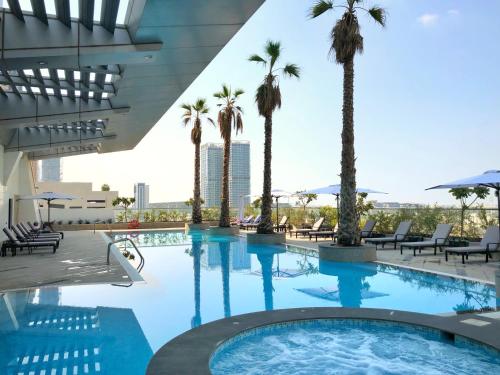Staybridge Suites Dubai Financial Centre, an IHG Hotel في دبي: مسبح بالنخيل ومبنى